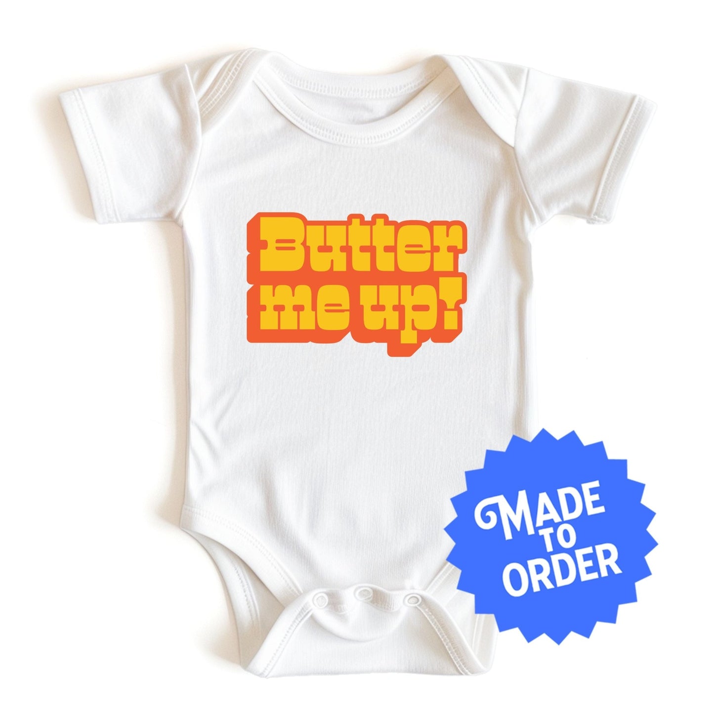 Chunky Deli product image: "Butter Me Up" onesie (100% cotton, natural color) laid flat on a white background, showcasing the envelope shoulders, short sleeves, three-snap closure, and the text "Butter Me Up" printed in orange and red across the chest.