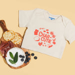 Chunky Deli product image: "Charcutie" bodysuit (100% cotton, natural color) folded in half next to a charcuterie board featuring olives and bread, playing off the bodysuit's graphic design. Peach background.