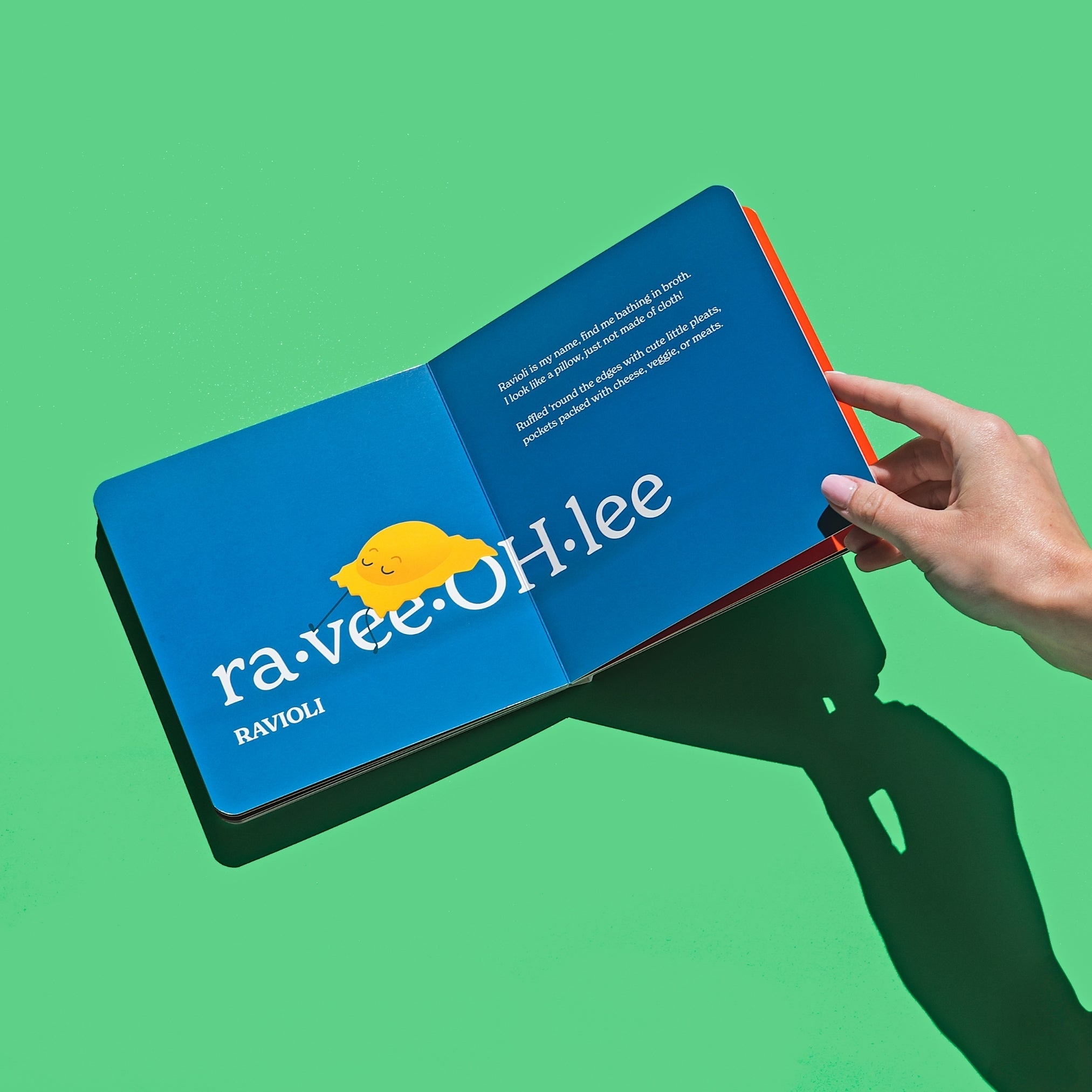 Chunky Deli product image: "Little Book of Pasta" open to the ravioli spread (blue page), featuring an illustration of a sleepy ravioli and its accompanying playful rhyme, held open by one hand against a green background.