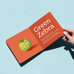 Open page of the 'Little Book of Tomatoes' board book titled featuring an illustration of a Green Zebra tomato with a playful rhyme on an orange background. Chunky Deli product image.