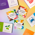 Chunky Deli "Fancy Flavors Collection" featuring five small hardcover books: "Gourmet Rainbow" by Caitlin Renee Steuer & Christina Sicoli, "Spice Rainbow" by Caitlin Renee Steuer & Christina Sicoli, and "Seafood Rainbow" by Caitlin Renee Steuer & Christi