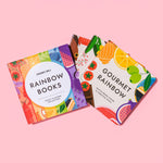 Four vibrant books from the Chunky Deli "Fancy Flavors Collection" are fanned out against a pink background. Each cover is a different color of the rainbow and features illustrations of gourmet foods. The front book reads "Gourmet Rainbow" and lists autho