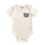 Chunky Deli product image: Natural-colored "Sous Chef" bodysuit (100% cotton) laid flat on a white background, showcasing the envelope shoulders and three-snap closure.
