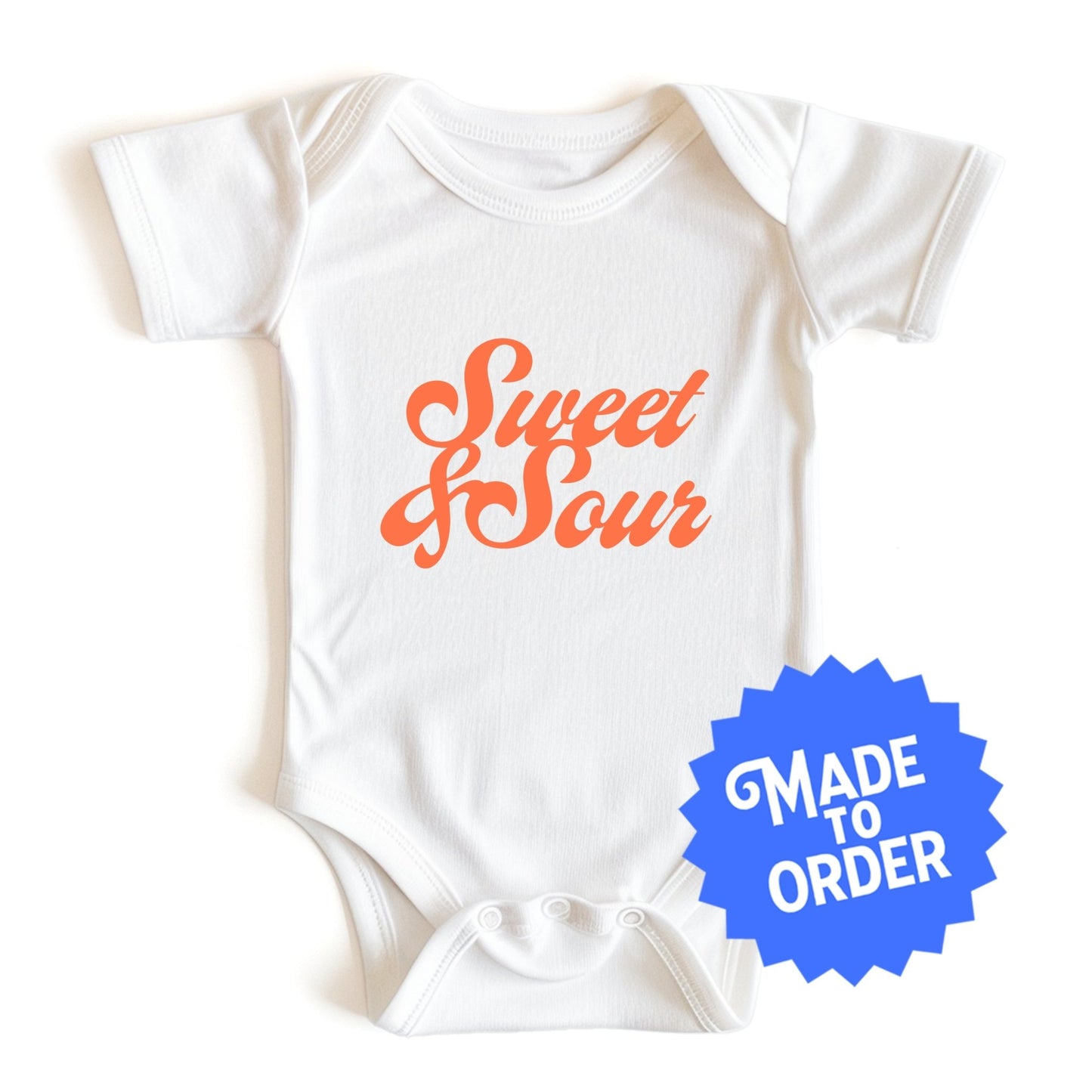 Chunky Deli product image: "Sweet and Sour" onesie (100% cotton, natural color) laid flat on a white background, showcasing the envelope shoulders, short sleeves, three-snap closure, and the text "Sweet and Sour" in orange cursive font on the chest.