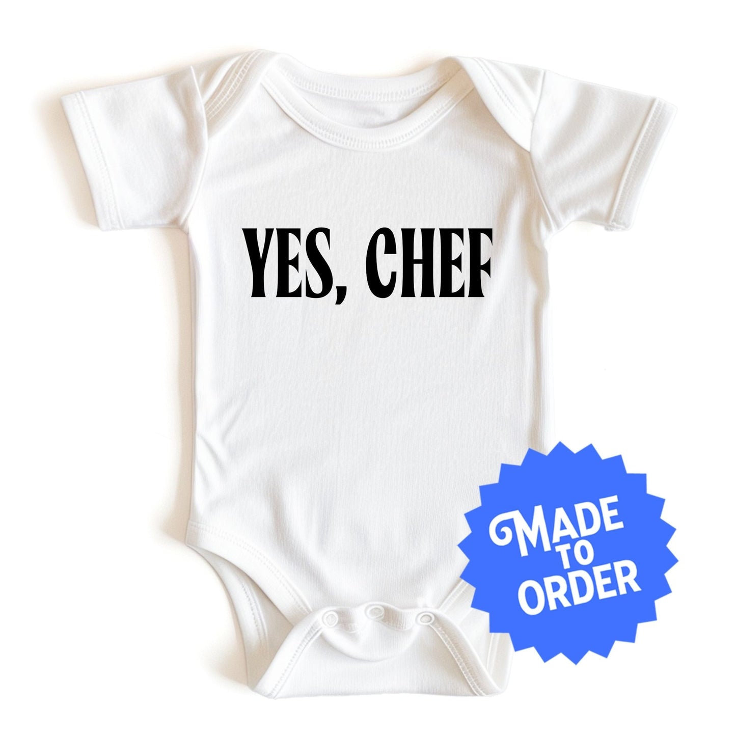 Chunky Deli product image: "Yes, Chef" onesie (100% cotton, natural color) laid flat on a white background, showcasing the envelope shoulders, short sleeves, three-snap closure, and the text "Yes, Chef" printed in black across the chest.