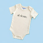 Product display image of the "Al Dente" baby bodysuit in natural cotton, laid flat on a pastel blue background. Chunky Deli product image.