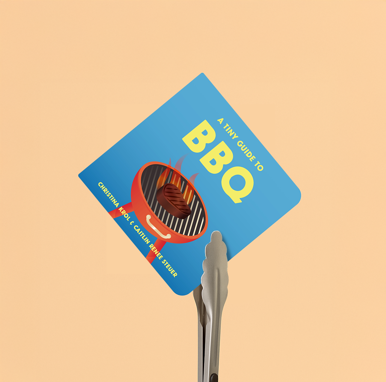 A book titled "A Tiny Guide to BBQ" by Christina Krol and Caitlin Renee Steuer is held by a pair of shiny silver tongs against a peach-colored background. The cover features an illustration of a glowing red grill with a piece of meat on it.