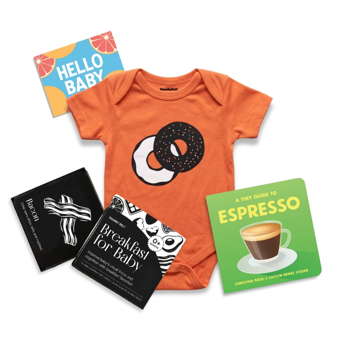 Chunky Deli product image of the breakfast Baby Bundle, including an orange everything bagel bodysuit, Black and white art cards and A Tiny Guide To Espresso Board Book By: Christina Krol & Caitlin Renee Steuer
