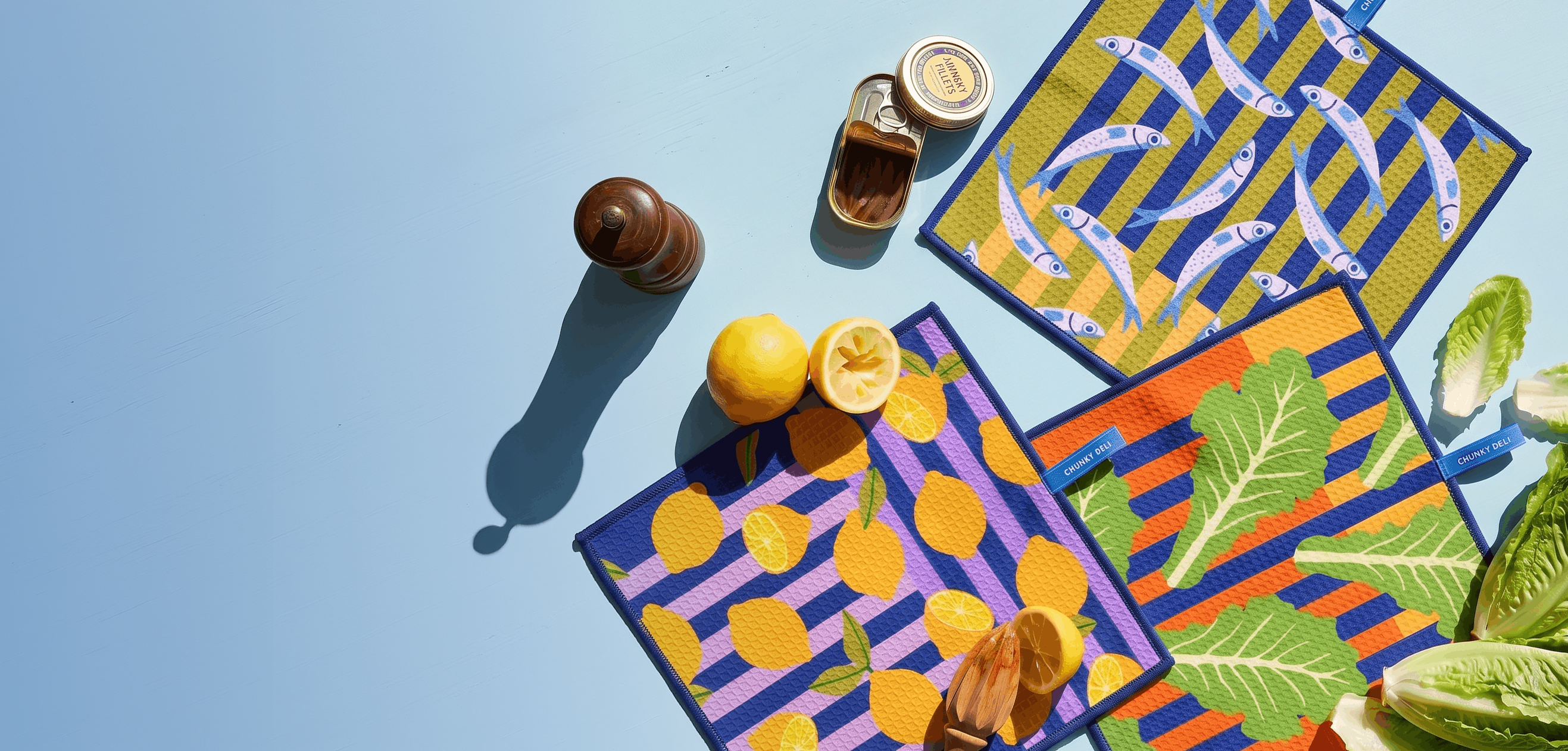 Colorful clean-up cloths with lemon, romaine lettuce and fish patterns on a blue background