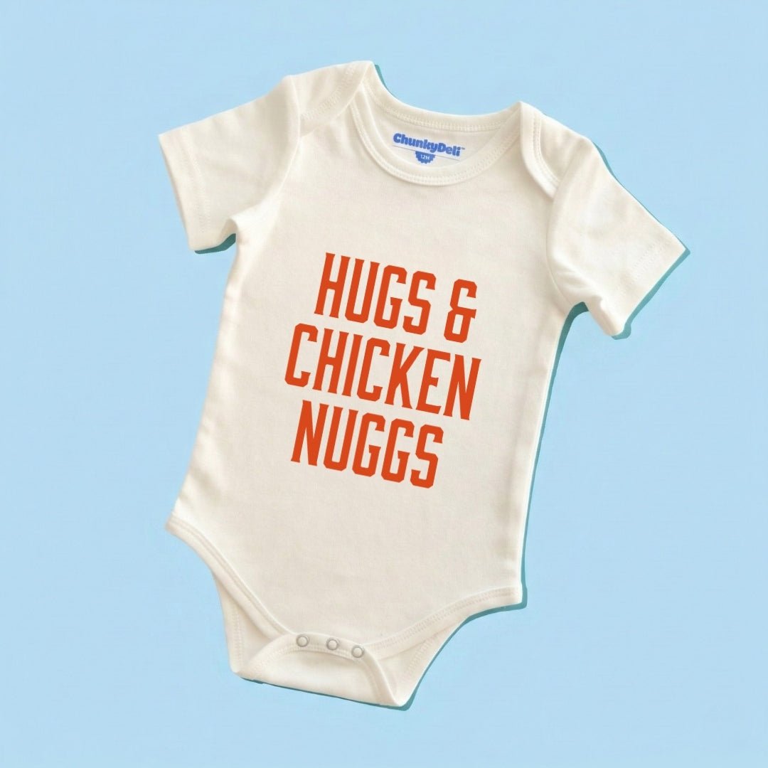 Chunky Deli product image: Natural-colored "Hugs & Chicken Nuggs" bodysuit (100% cotton) laid flat on a pastel blue background, showcasing the envelope shoulders and three-snap closure.