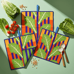 Chunky Deli lifestyle image of colorful kitchen towels with leaf pattern on a green table with vegetables and salad forks.