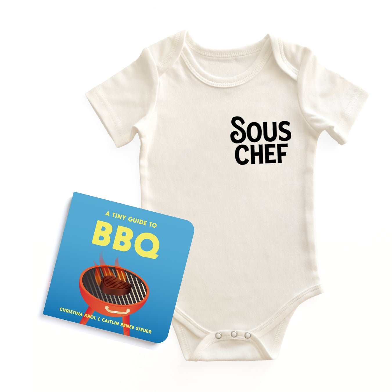  Chunky Deli "BBQ Baby Starter Pack" featuring a white, 100% cotton, short sleeve baby bodysuit with black "SOUS CHEF" text, accompanied by the "A Tiny Guide to BBQ" board book by Christina Krol & Caitlin Renee Steuer, all on a white background.