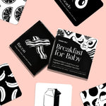 Chunky Deli Breakfast for Baby box surrounded by scattered high-contrast black and white art cards featuring bacon and milk.