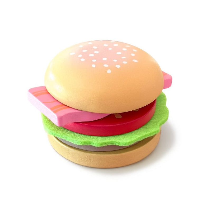 multi-layered toy hamburger from the Chunky Deli range. The stack, from top to bottom, features a light-brown wooden bun top with painted white sesame seeds, a wavy green felt lettuce leaf, a thick red wooden tomato slice, a rectangular pink wooden block representing bacon with dark stripes, a dark-brown wooden meat patty, and a light-brown wooden bun base
