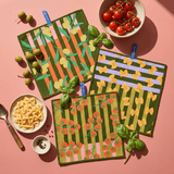 Chunky Deli product image of a set of three patterned cloths on a pink background with food items.