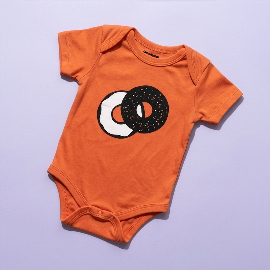 Chunky Deli Product Image: Orange baby onesie with a two tone graphic of an everything bagel with cream cheese on a purple background