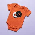 Chunky Deli Product Image: Orange baby onesie with a two tone graphic of an everything bagel with cream cheese on a purple background