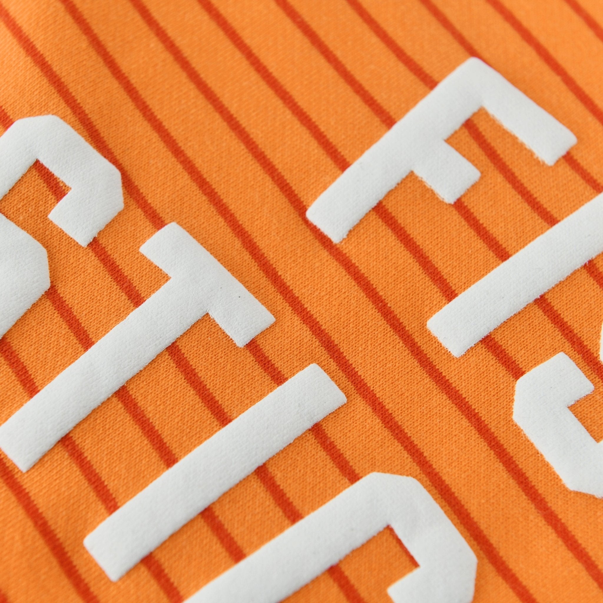 Close-up of the vibrant orange striped fabric and lettering on the Fish Sticks Kids Crewneck Sweater.