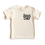 Chunky Deli product image: Toddler tee in 100% cotton, short sleeve, beige/natural color. Features printed text reading "Sous Chef" on the upper left chest, positioned like a breast pocket.