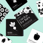 Top-down flat lay of the "Garden for Baby" art cards, with the box in the center, on a pastel green surface.
