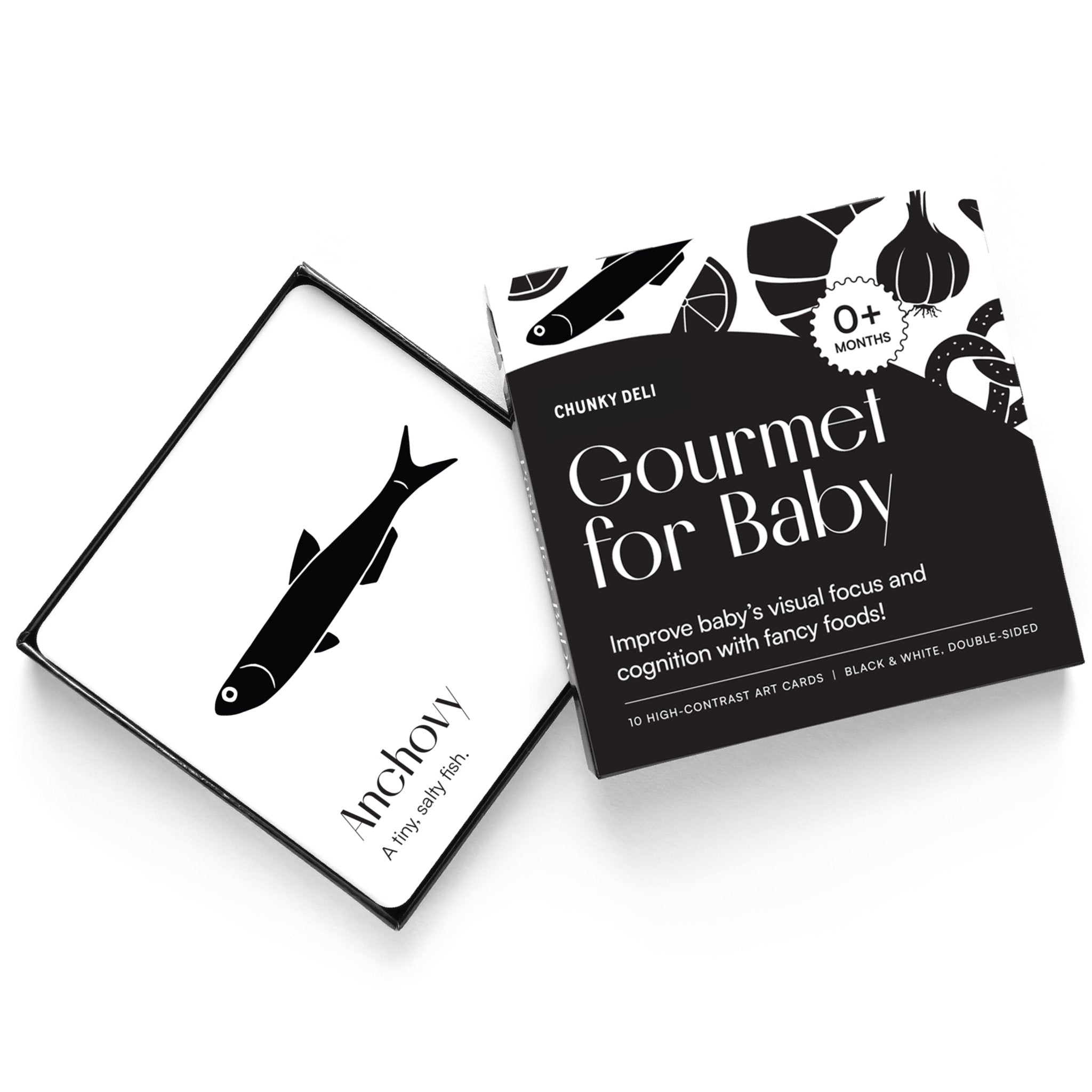 High-angle product shot of a black and white "Gourmet for Baby" art card set. An anchovy card rests on the open box.