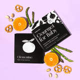 Top-down product shot of the "Gourmet for Baby" art cards, with oranges, pistachios, pretzels, and asparagus.