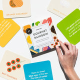  Chunky Deli product image: "Gourmet for Rainbow" art cards box held in place by a model's hand, surrounded by cards from the set, some showing sight word poems and rhymes, others displaying illustrations and titles.