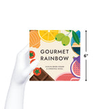Hand holds up "Gourmet Rainbow," a square, green children's book. The cover features stylized foods. Measuring 6 inches. By Caitlin Renee Steuer & Christina Sicoli 