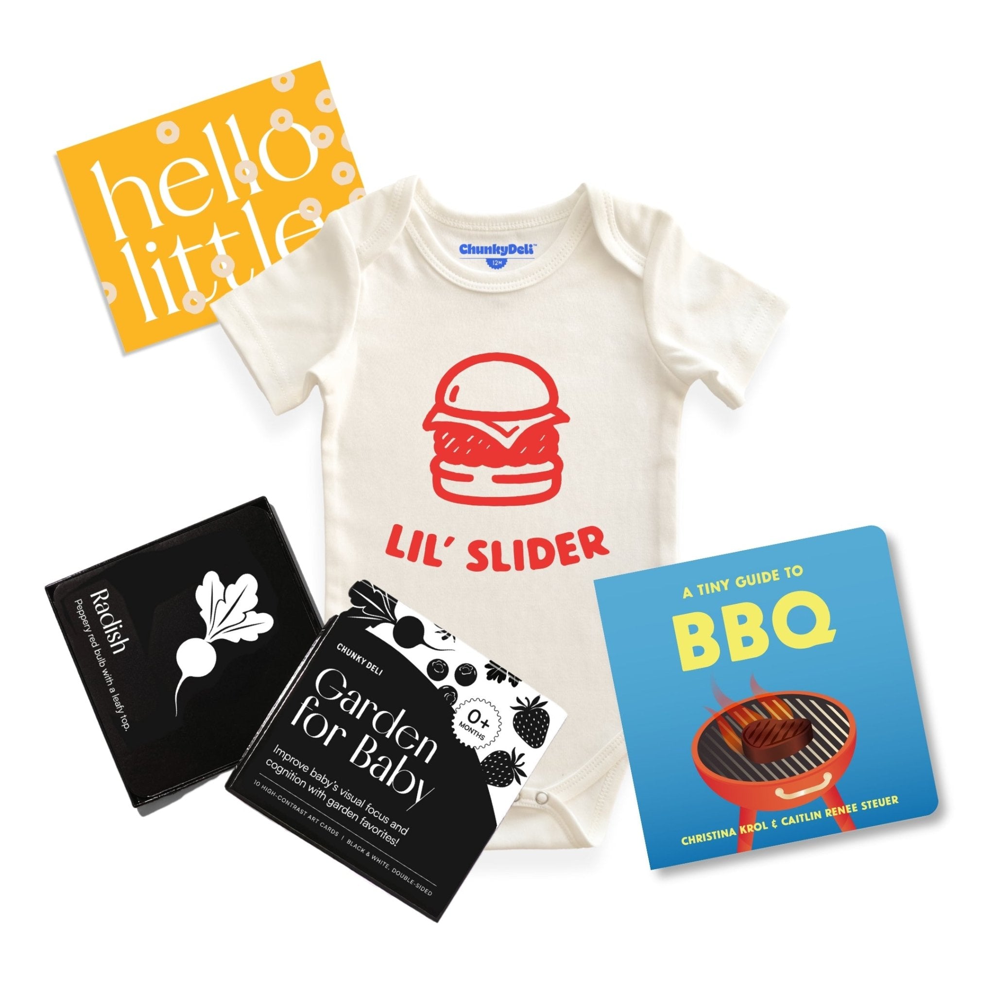 Chunky deli product image of the grillmaster baby bundle, top down view of a baby onesie with a bold graphic and "lil' Slider" Printed in orange font. There is also a tiny guide to BBQ and Garden for Baby art cards. 