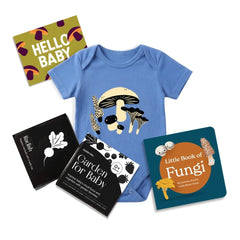 Flat lay product image features blue mushroom baby bodysuit, black and white high contrast garden for baby art cards, little book of fungi and a "hello Baby" gift note. 