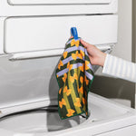 Chunky Deli product image of a hand holding a colorful Italian farfalle pasta patterned towel in front of a washing machine.