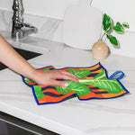 Chunky Deli Product image of a person holding a colorful romaine leaf-patterned cleanup cloth on a kitchen counter.