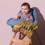 Chunky Deli product image of a Blue high chair holding a baby with a colorful striped tomato towel draped over it against a pink background