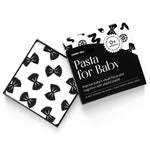 High-angle product shot of a black and white "Pasta for Baby" art card set. A card with a bow tie pasta pattern rests on the open box.