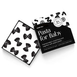 High-angle product shot of a black and white "Pasta for Baby" art card set. A card with a bow tie pasta pattern rests on the open box.