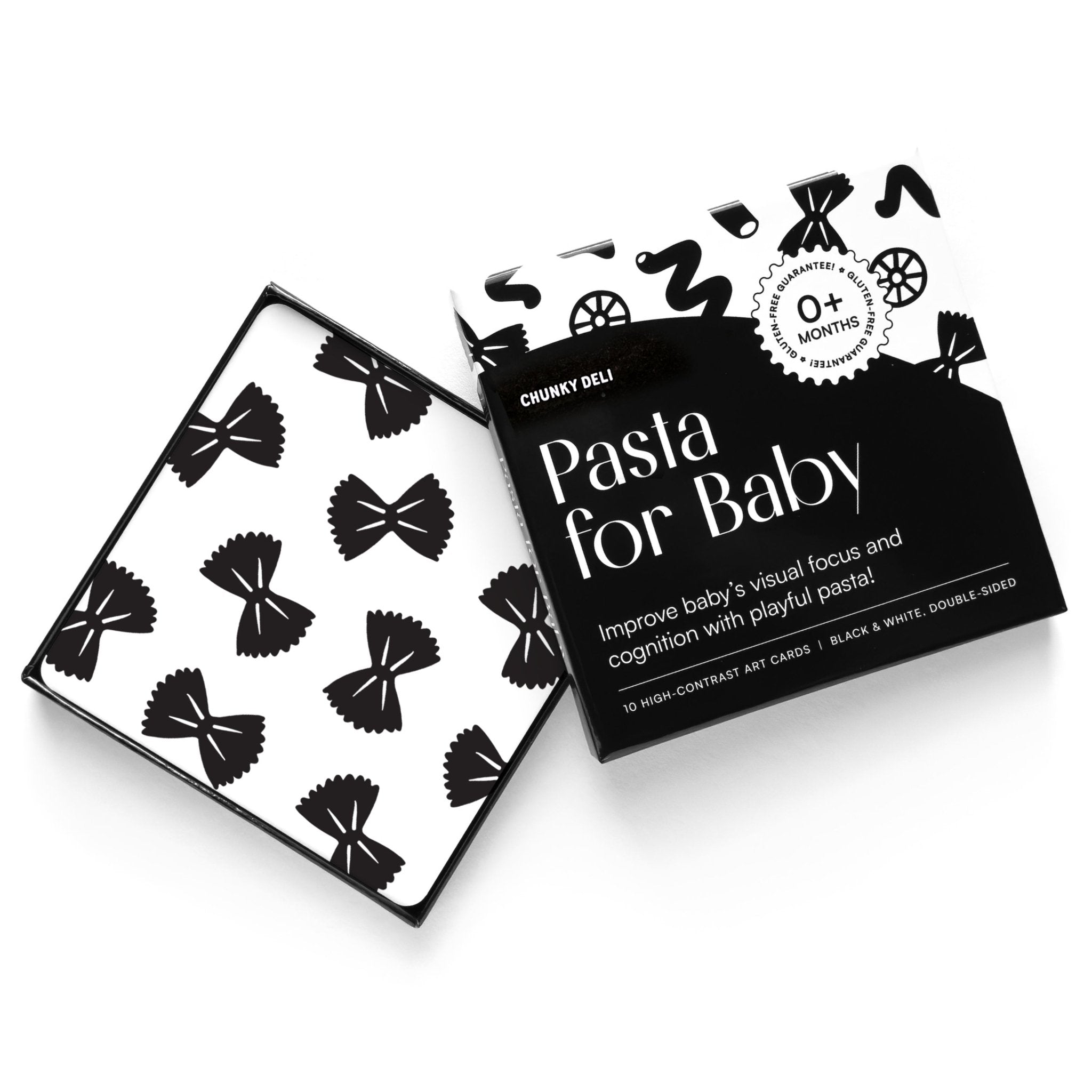 High-angle product shot of a black and white "Pasta for Baby" art card set. A card with a bow tie pasta pattern rests on the open box.