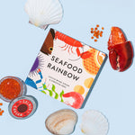  Chunky Deli "Seafood Rainbow" board book by Caitlin Renee Steuer & Christina Krol, featuring a colorful cover with illustrations of various sea creatures and seafood, surrounded by real seafood elements such as a lobster claw, salmon caviar, and various 