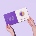  "Seafood Rainbow" by Christina Krol and Caitlin Renee Steuer is held open. The left page has a poem about a purple urchin on a purple background. The right page features an illustration and the name "PURPLE URCHIN" on a white background.