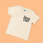 Chunky Deli product image: Toddler tee in 100% cotton, short sleeve, beige/natural color. Features printed text reading "Sous Chef" on the upper left chest, positioned like a breast pocket.