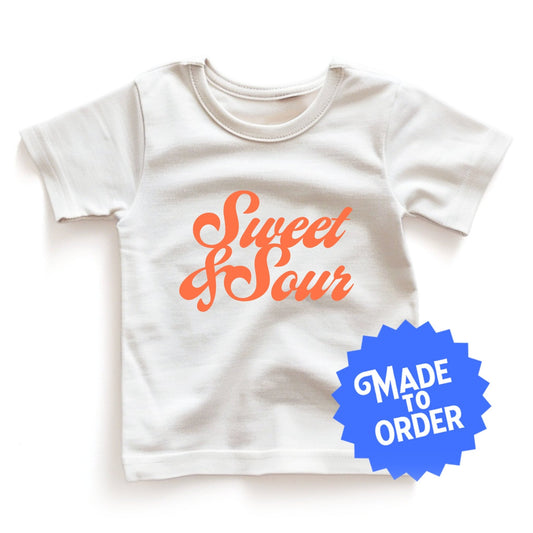 Product display image of the "Sweet & Sour" kids and toddler t-shirt in natural cotton, laid flat on a white background. Chunky Deli product image.