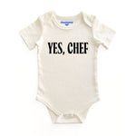 Chunky Deli product image: Natural-colored "Yes, Chef!" bodysuit (100% cotton) laid flat on a white background, showcasing the envelope shoulders and three-snap closure.