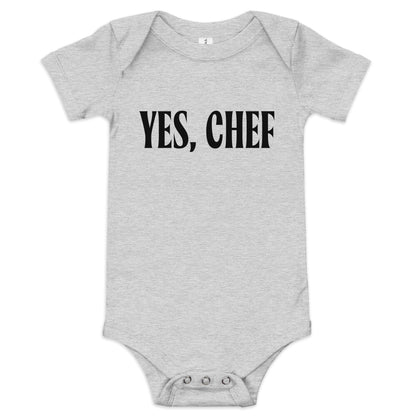  Chunky Deli product image: "Yes, Chef" onesie (100% cotton, grey color) laid flat on a white background, showcasing the envelope shoulders, short sleeves, three-snap closure, and the text "Yes, Chef" printed in black across the chest.