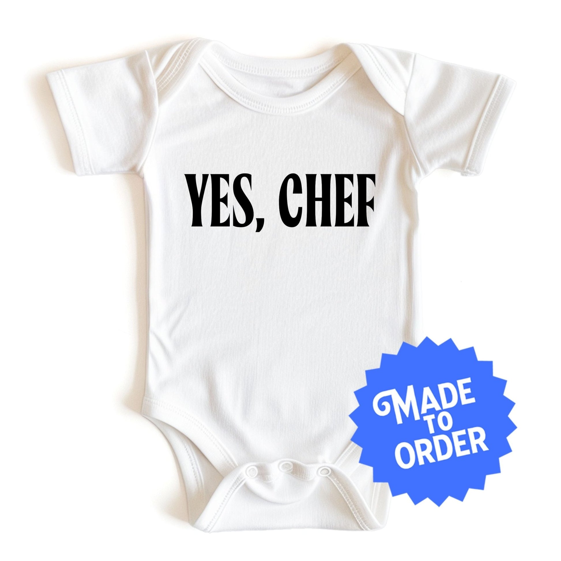 Chunky Deli product image: "Yes, Chef" onesie (100% cotton, natural color) laid flat on a white background, showcasing the envelope shoulders, short sleeves, three-snap closure, and the text "Yes, Chef" printed in black across the chest.